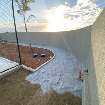 Execução do preparo da base com pó de pedra para início do assentamento do piso intertravado na pista de caminhada do clube.